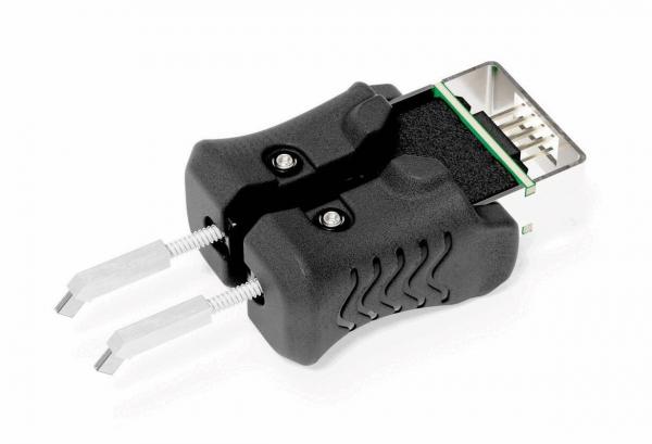 Das Bild zeigt ein schwarzes Gerät mit zwei grifffreundlichen Seiten, die wie Gummi aussehen. An einem Ende ist ein Verbindungselement sichtbar, das für elektrotechnische Anwendungen genutzt wird.