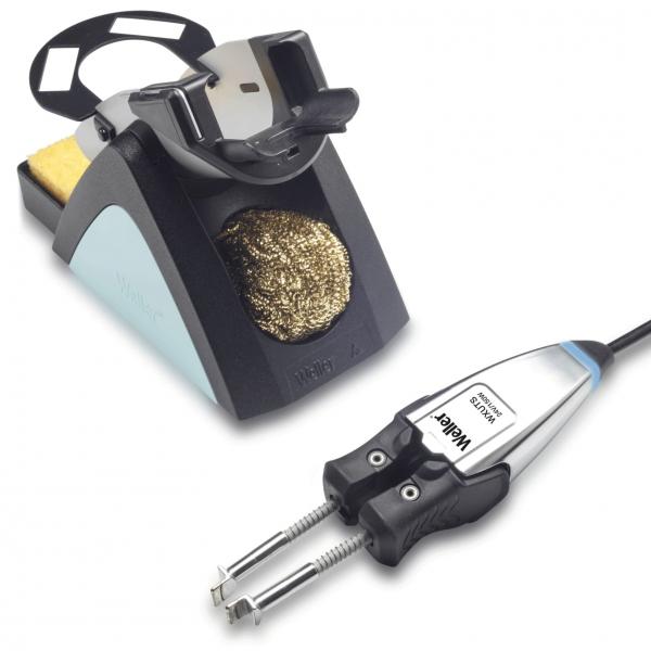The image shows a soldering iron with a holder. The holder has a round opening and contains a brass cleaning spiral. A pressure device is attached to the cable of the iron.