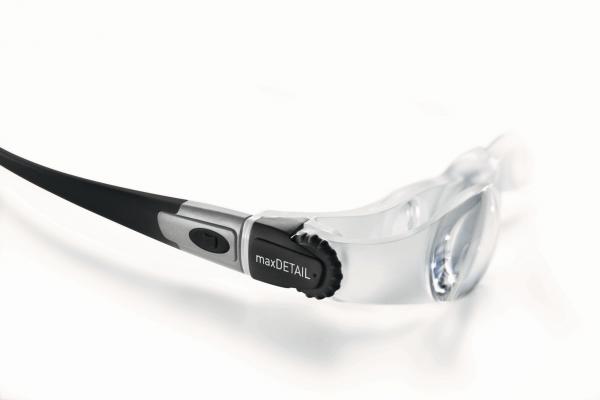 The image shows a pair of glasses with transparent lenses. On one temple, there is a black control panel with a button and a dial for adjustment.
