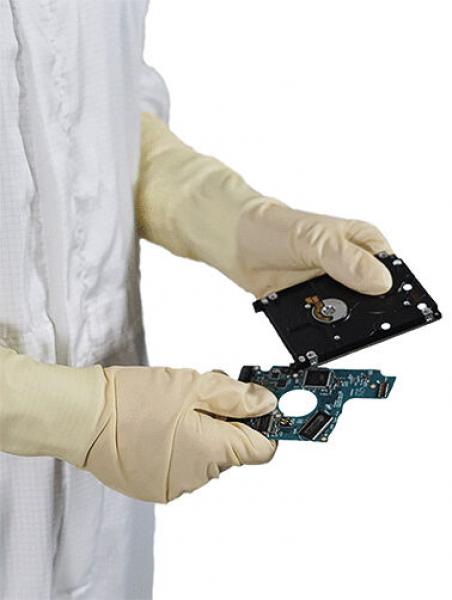 Eine Person in weißen Handschuhen hält zwei Teile eines Computerlaufwerks. Das obere Teil ist schwarz und hat eine runde Öffnung, das untere ist grün mit feinen Schaltkreisen.
