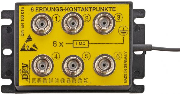 Das Bild zeigt eine gelbe Erdungsbox mit sechs runden Kontaktpunkten. Darunter steht "6 ERDUNGS-KONTAKTPUNKTE" sowie technische Hinweise. Die Box hat eine schwarze Rückseite und ein Kabel.