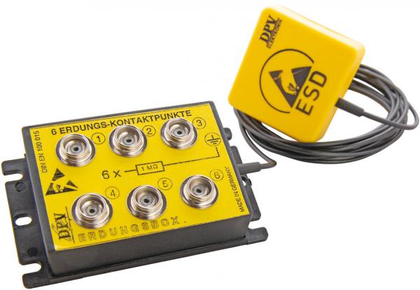 Das Bild zeigt ein gelbes Erdungskontaktfeld mit sechs runden Anschlüssen. Daneben befindet sich ein gelbes ESD-Zeichen mit einem langen Kabel. Es dient zur elektrostatischen Entladung.