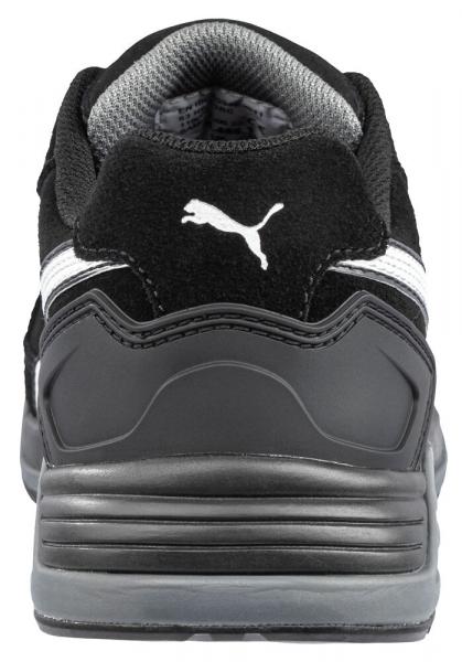 The image displays the rear view of a black shoe. It features a gray sole and a white stripe. A prominent Puma logo is visible. The shoe appears sporty and modern.
