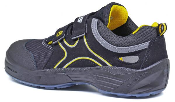 Der Schuh ist sportlich, mit einer schwarzen und grauen Oberfläche. Gelbe Akzente entlang der Seiten und am inneren Rand. Er hat einen Klettverschluss und eine robuste Sohle.