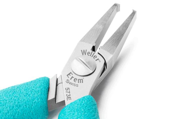 The image shows a small, precise pair of pliers with two pointed jaws. The handle is in a bold turquoise, and the pliers have a silver metal surface with an engraved brand.