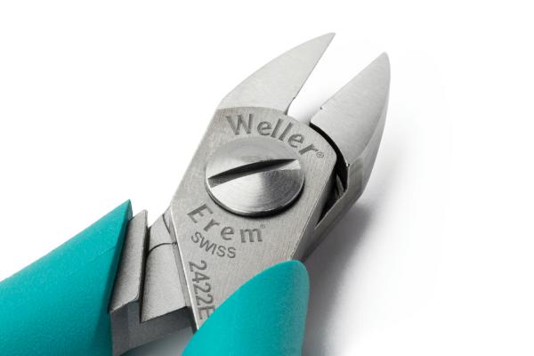 Das Bild zeigt eine Zange mit einer silbernen, glänzenden Klinge. Der Griff ist türkisfarben. Auf der Zange sind die Marken "Weller" und "Erem" eingraviert. Sie hat spitze, geschlossene Kanten.