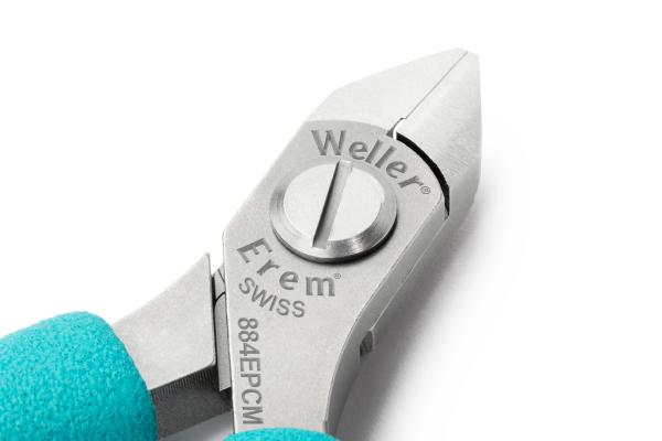The image shows a precise pair of pliers with a silver metal surface. The handle is turquoise and ergonomically designed. Brand names and brief information are engraved on the pliers.