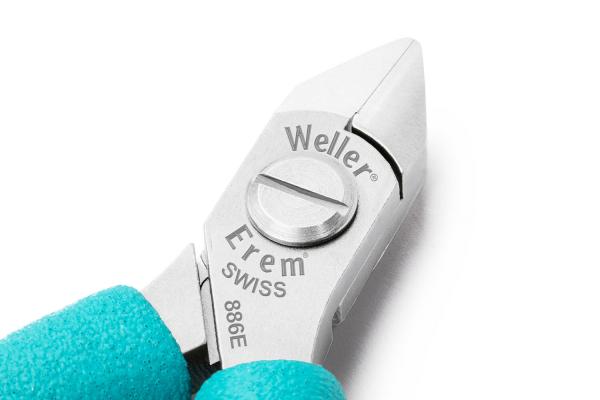 Das Bild zeigt eine silberne, spitze Zange mit einem kurzen, runden Griff. Der Griff hat eine türkise Gummierung. Auf der Zange sind die Markenbezeichnungen ?Weller? und ?Erem? eingraviert.