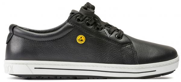 Der Schuh ist ein schwarzer Sneaker aus Leder mit runder Spitze. Er hat eine glatte Oberfläche, eine gelbe Markierung an der Seite und eine weiße Sohle mit leichtem Profil.