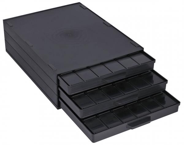 Das Bild zeigt eine schwarze, flache Aufbewahrungsbox mit vier Schubladen. Die Schubladen sind unterschiedlich tief und haben zahlreiche kleine Fächer für die Organisation.