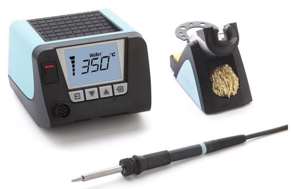 The image displays a soldering system with a heating station in light blue and black. It features a digital display and buttons. Next to the station, there is a soldering iron with a cable and a holder.