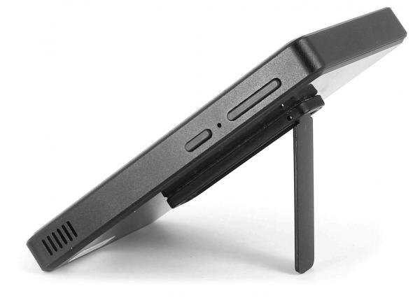 The image shows a thin, black device that is sleek and flat. It stands on a small, fold-out stand. Buttons are visible on the side.