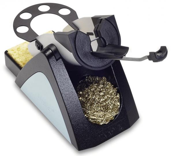 The image shows a small, black and gray metal sharpener with a holder on top for pencils. On the side, there is a container for wood shavings. A lever allows for the turning of the pencil.