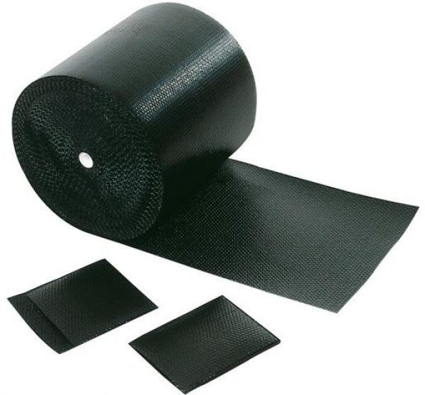 Das Bild zeigt eine schwarze Rolle mit rutschfestem Material, von der ein Stück abgerollt ist. Daneben liegen zwei kleinere Rechtecke aus dem gleichen Material.