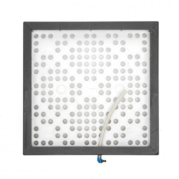 Das Bild zeigt eine quadratische graue Platte mit vielen kleinen runden Löchern. An einer Seite befindet sich ein dünner Schlauch, der herausragt. Die Platte scheint aus Kunststoff zu sein.
