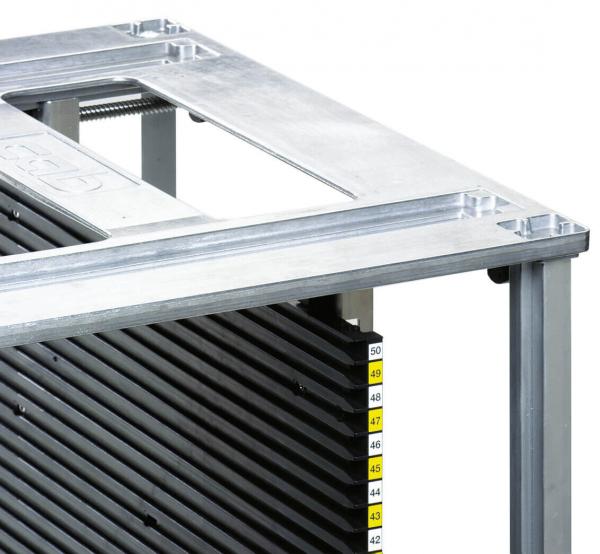 The image displays a metal frame with a flat surface and a vertical arrangement of black, ridged plates. Numbered markings are visible on the left side.