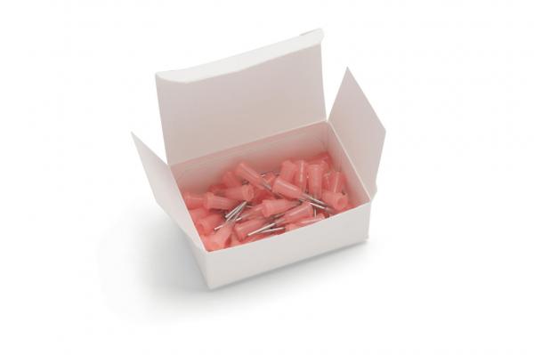 Eine offene, weiße Schachtel enthält mehrere kleine, pinkfarbene Teile mit metallischen Spitzen. Die Teile scheinen Zubehör oder Halterungen zu sein, die in der Schachtel chaotisch angeordnet sind.