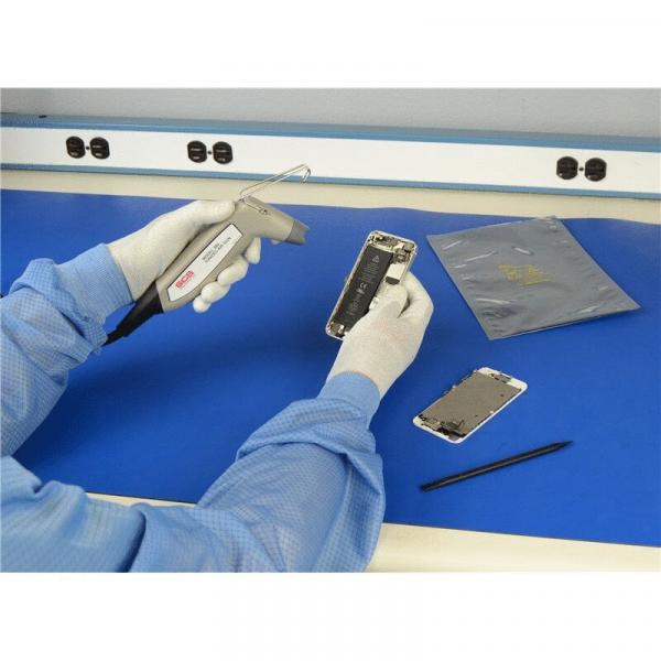 In the image, you can see a hand in a blue glove holding a smartphone with a tool. On a blue table, there is another smartphone and a black pen.