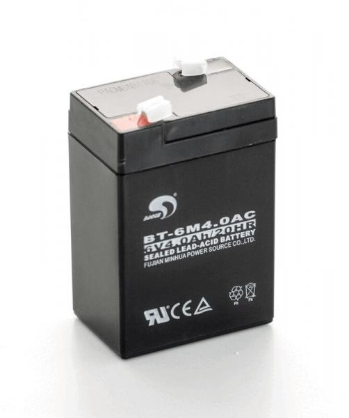 The image shows a black lead-acid battery. It has a rectangular shape with a transparent lid. On the front, technical data and symbols are printed.
