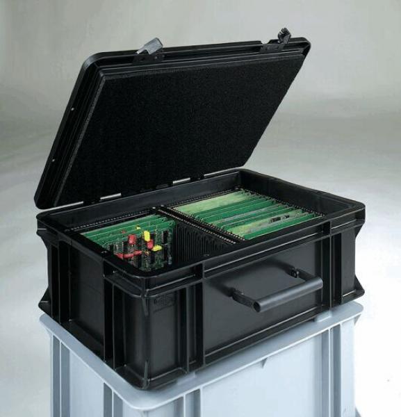 The image shows a black, box-shaped container with an open lid. Inside, green circuit boards and various colorful buttons and connectors are visible. The box is placed on a gray surface.