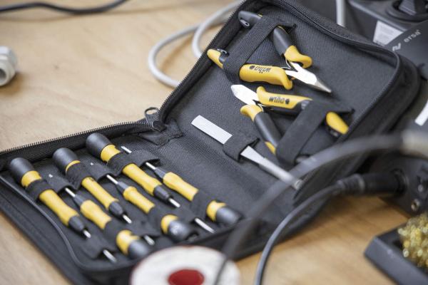 The image shows a tool bag. Inside, there are several screwdrivers and a small pair of pliers, all with black handles and yellow accents. The bag is closed and flat.