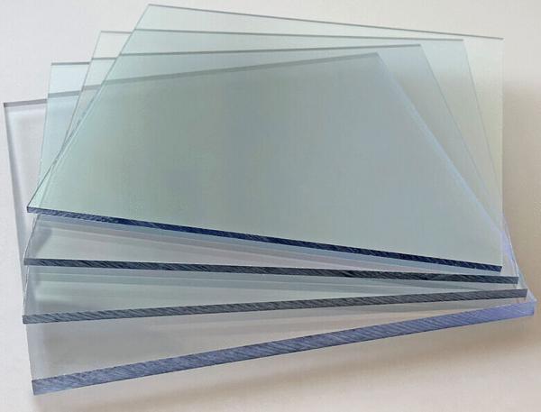 In the image, several transparent glass panes are stacked on top of each other. They are rectangular and slightly shimmering, arranged on a light background.