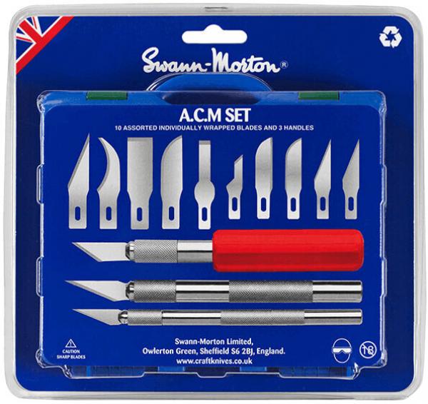 Das Bild zeigt ein Set mit verschiedenen Skalpellklingen und zwei Griffen in einer blauen Verpackung. Eine Klinge hat einen roten Griff, die anderen sind in silberner Farbe.