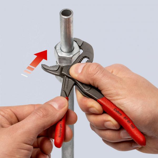 Das Bild zeigt zwei Hände, die jeweils ein Werkzeug halten. Eine Hand benutzt eine verstellbare Zange, während die andere einen Metallrohr mit einer Mutter festhält.