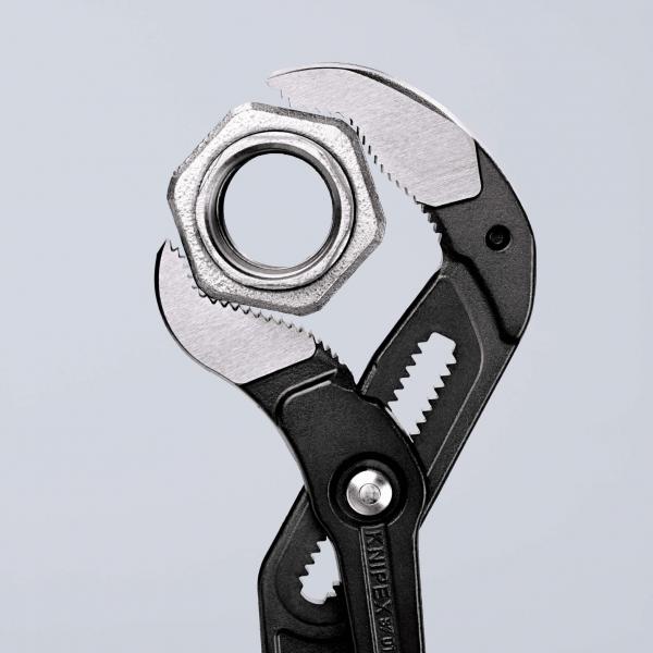 The image shows an adjustable wrench gripping a metal nut. The wrench has black handles and a shiny, silver working surface with sharp edges.