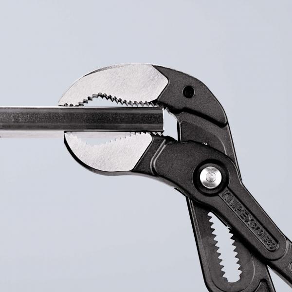 The image shows a pair of pliers with a long, narrow gripping surface. The pliers have a black plastic coating and metal gripping jaws with teeth for better grip.