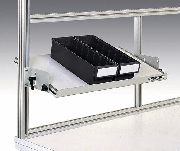 The image shows a warehouse-like shelving system with a pull-out shelf. On it are two black plastic containers with space for compartments, attached to a sturdy, silver frame.