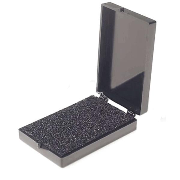 Das Bild zeigt eine kleine, schwarze Box, die geöffnet ist. Der Innenbereich ist mit einer schaumigen, strukturierten Oberfläche ausgekleidet. Die Box hat eine rechteckige Form und einen Deckel.