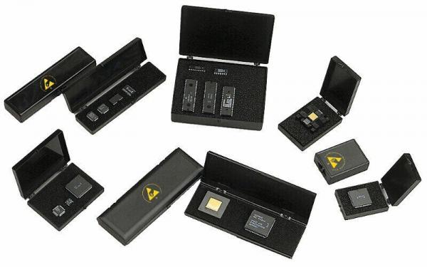 Das Bild zeigt mehrere schwarze Schatullen, die geöffnet sind. In ihnen befinden sich kleine elektronische Bauteile, möglicherweise Computerchips oder Speichermodule. Einige Schatullen haben ein Warnsymbol.
