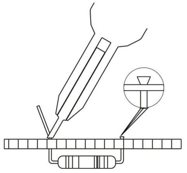 Das Bild zeigt einen technischen Aufbau: Eine Zange hält einen kleinen Bauteil über einer Kunststoffplatine. Eine Lupe vergrößert das Bauteil, das auf der Platine platziert wird.