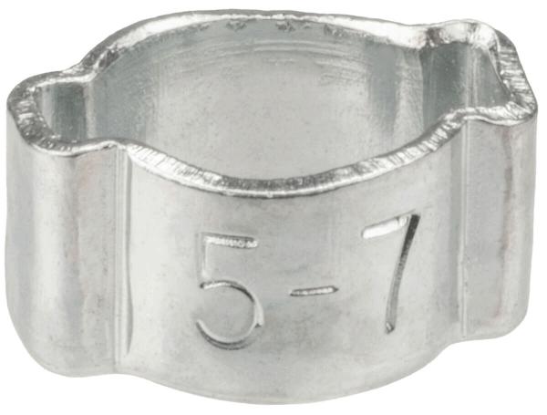 Das Bild zeigt eine kleine, silberne Halterung aus Metall. Sie hat eine runde Öffnung in der Mitte und ist oben und unten leicht gewellt. Auf der Seite sind die Zahlen "5-7" eingraviert.