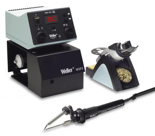 The image shows a soldering station with a digital temperature controller on top, a black base, and a soldering iron on the left side. On the right, there is a holder with cleaning wool.