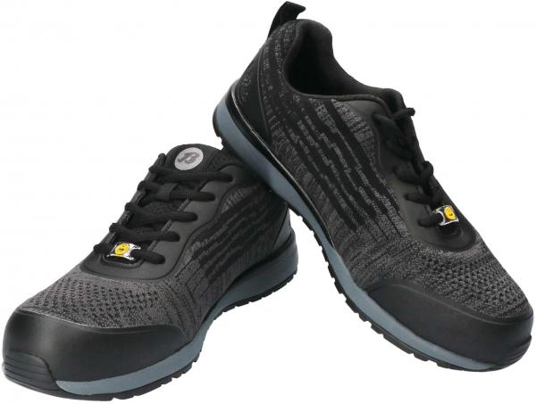 Das Bild zeigt ein Paar sportliche schwarz-graue Sneakers. Sie haben eine textile Oberfläche mit strukturiertem Muster und eine graue Gummisohle. Die Schnürsenkel sind schwarz.