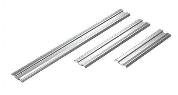 Auf dem Bild sind drei parallel angeordnete, matte Aluminiumprofile in verschiedenen Längen zu sehen. Sie haben eine rechteckige Form mit einer leicht gewölbten Oberseite.