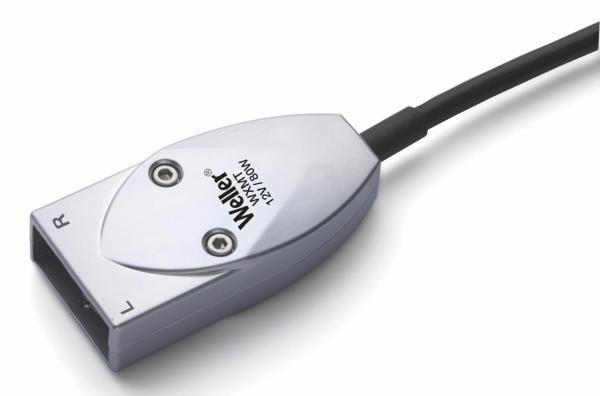 Das Bild zeigt einen silbernen Stecker mit zwei runden Öffnungen für Anschlüsse, einem Kabel, das herausführt, und der Aufschrift "Weller". Die Form ist oval und flach.