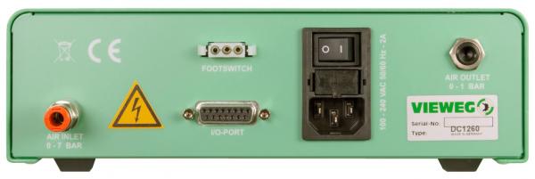 The image shows the back of a green device. It has various connections: for air supply, a foot switch, an I/O port, and a power connection. A safety sign is also visible.