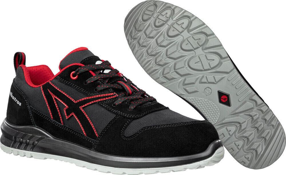 Das Bild zeigt einen sportlichen Schuh in Schwarz mit roten Akzenten. Die Sohle ist griffig und hat ein strukturiertes Muster. Der Schuh hat Schnürsenkel und eine verstellbare Lasche.