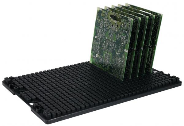 Das Bild zeigt mehrere grüne Leiterplatten, die aufrecht auf einem schwarzen, gummierten Halter gestapelt sind. Der Halter hat eine strukturierte Oberfläche aus kleinen Erhebungen.