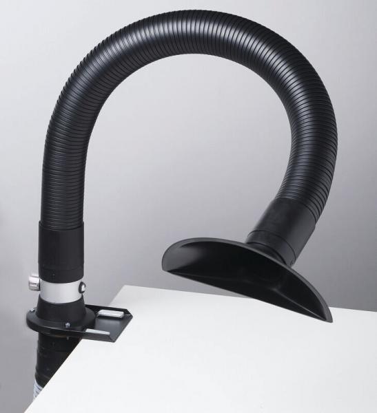 The image shows a flexible, black hose attached to a table. At the end of the hose, there is a round, open shaft. The hose is likely used for extracting fumes or dust.