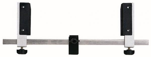 The image displays a metal device with a long central rod. At both ends, there are black, padded holders. In the center, there is a small black screw.