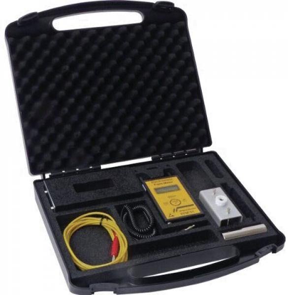 The image shows a black suitcase that is open. Inside, there are various technical devices, including a yellow measuring device, cables, and a small metal component, all neatly arranged.