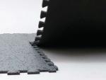 Preview: The image shows a black, textured surface made of thick mats stacked at one edge. One mat is slightly lifted, while the other is flat. The surface has a rough texture.