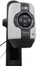 Preview: The image shows a device for optical magnification. It has a round, central button with several control knobs around it and is mounted on a stable, black stand.