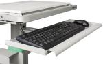 Preview: The image shows a desk with a pull-out keyboard tray. On the tray, there is a black, flat keyboard and next to it a black computer mouse. The surface is light gray.