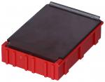 Preview: The image shows a rectangular object with a red plastic base and a smooth, gray or black top. The surface is flat and sits on a raised edge.