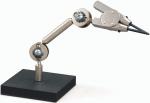 Preview: Das Bild zeigt eine metallische Halterung mit einem beweglichen Arm, der mit einer Zange oder einem Stift endet. Der Arm ist auf einem quadratischen schwarzen Sockel montiert.